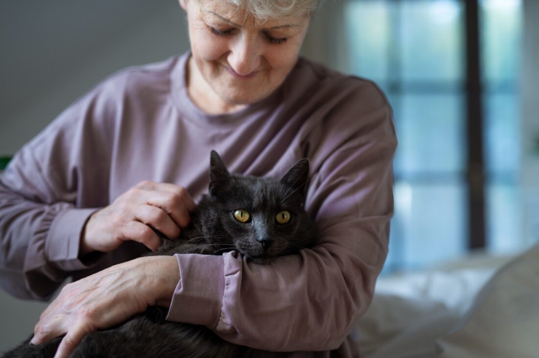 Happy senior woman with cat resting in bed at home